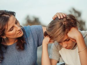 woman comforting young teenager with hands on head
